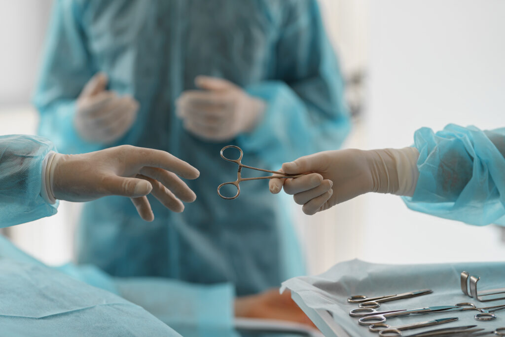 Assistant hands out instruments surgeon during surgery in the operating room